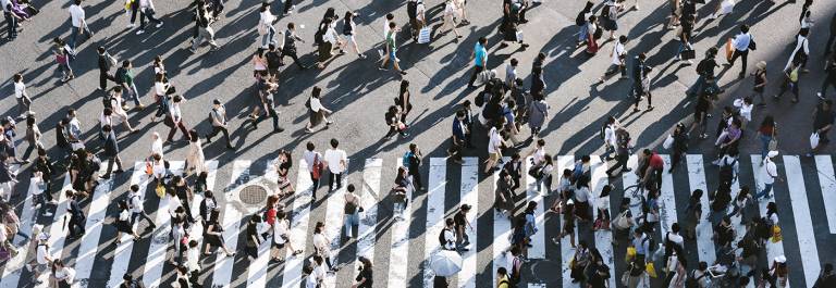 Photo of many people walking across a road crossing