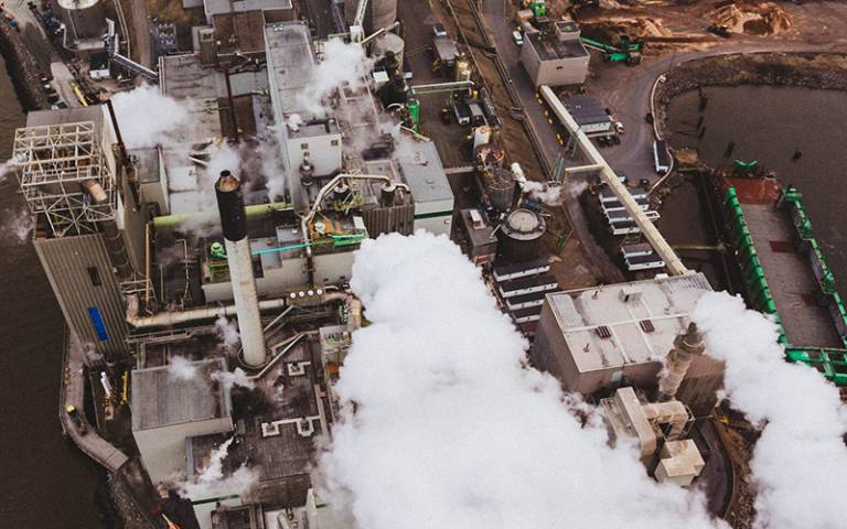 Photo shows an aerial view of a power station with thick grey smoke billowing from chimneys.