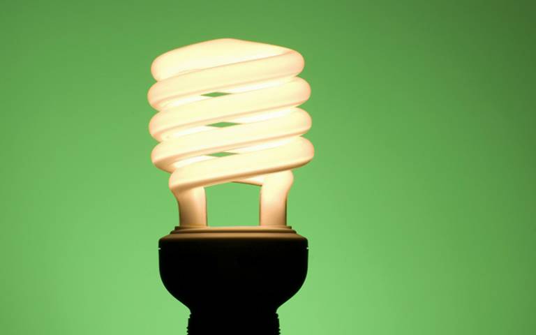 Image shows an energy saving light bulb against a green background.