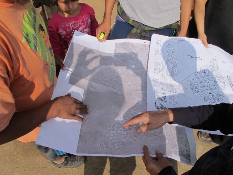 Photo shows locals in Lima, Peru, holding an aerial map of the area