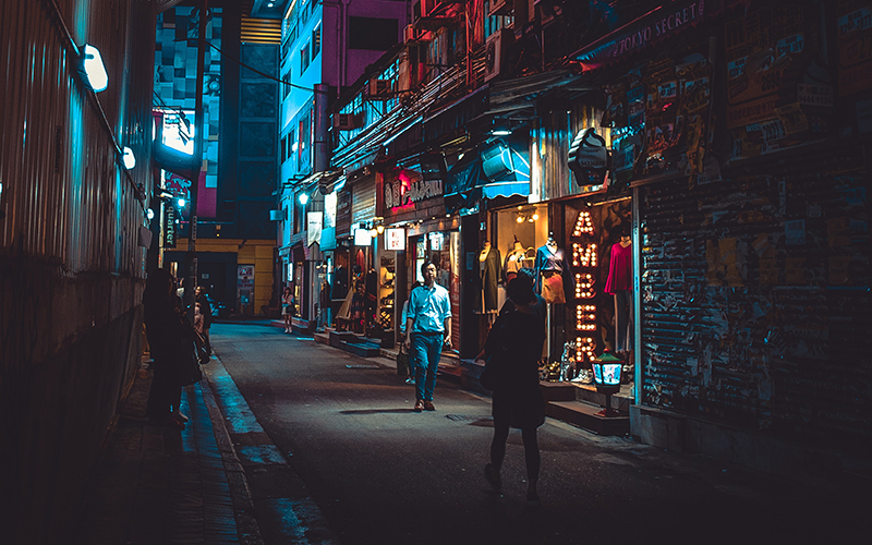 Image of people walking in a lit street at night