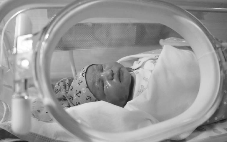 Baby in an incubator in black and white