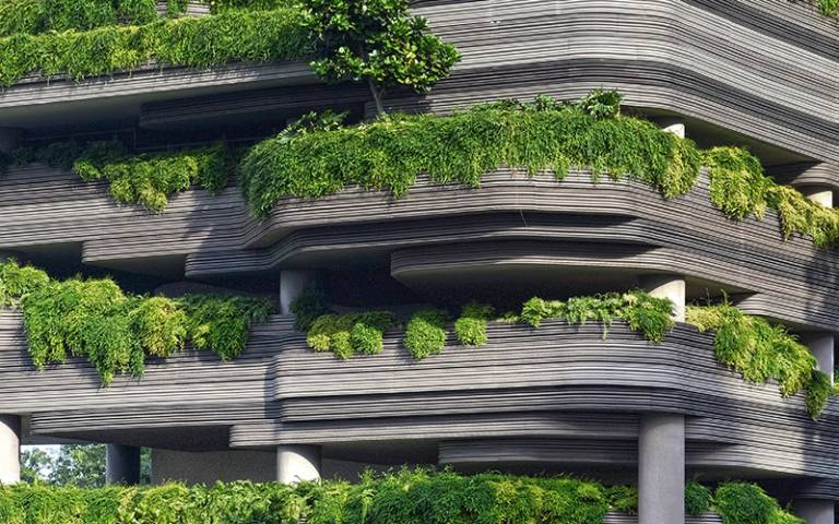 Modern high rise building with plants growing around the spaces in the facade