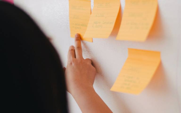 woman pointing to orange post it notes on a board