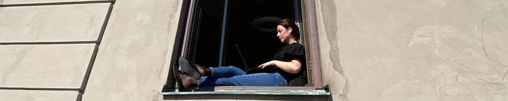 woman sits in the window working on laptop
