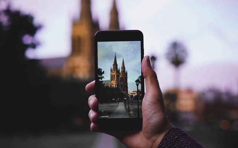 Photo shows a phone taking a photograph of a church and street