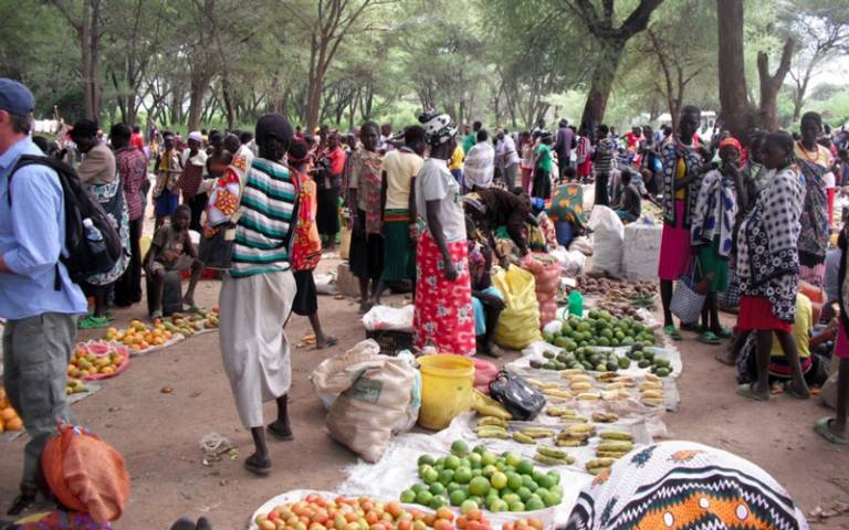A group of people buying and selling fruit and vegetables at an outdoor market in Africa