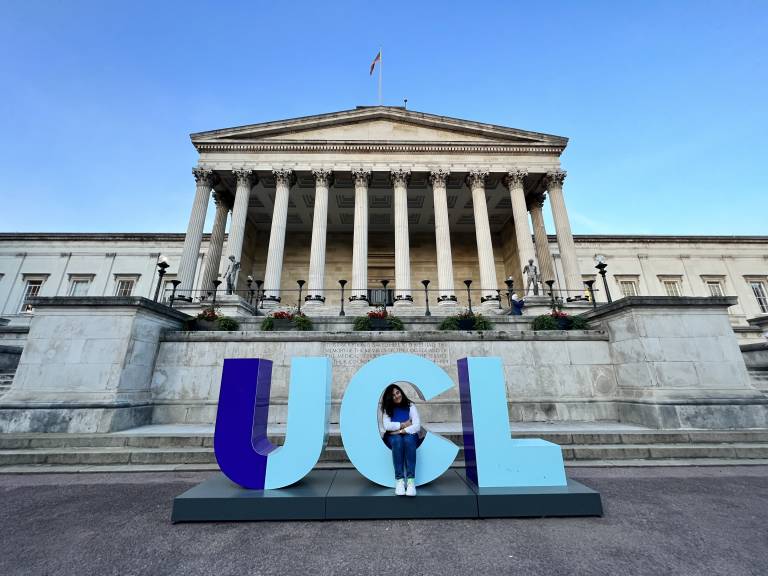 Student Mara Torres Pinedo at the 'UCL' letters in front of the Portico building on the UCL campus