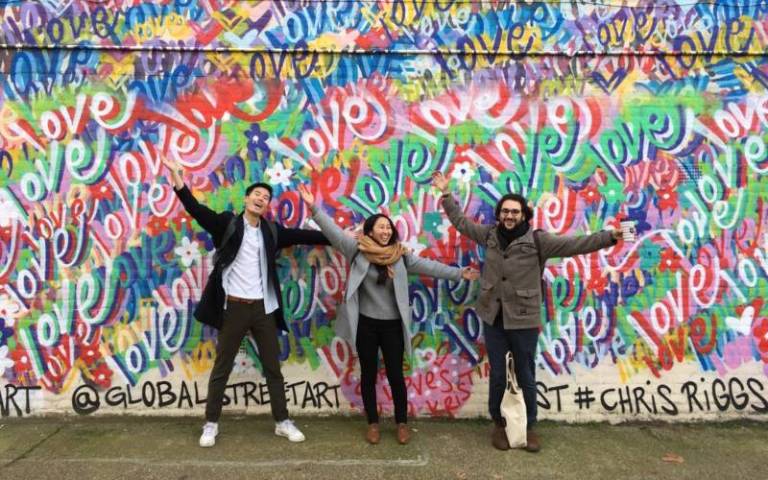 A group of students standing in front of a graffiti wall