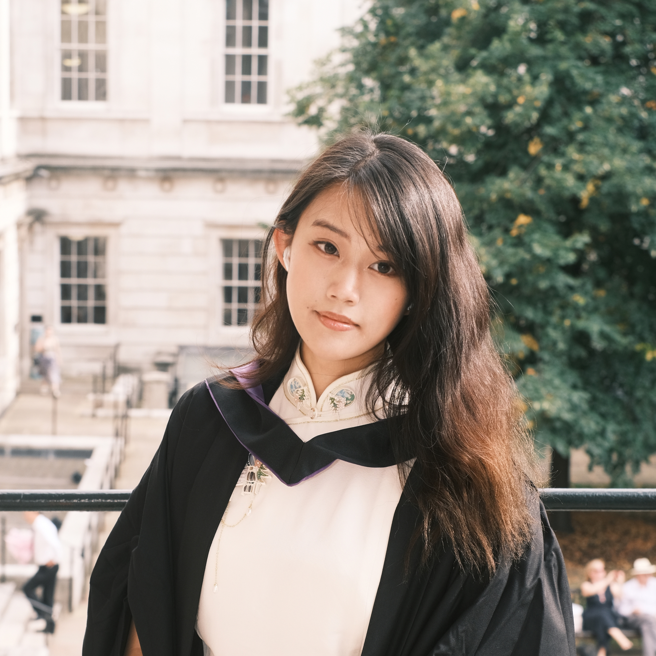 Photograph of Yuxi in graduation robes at the UCL Portico