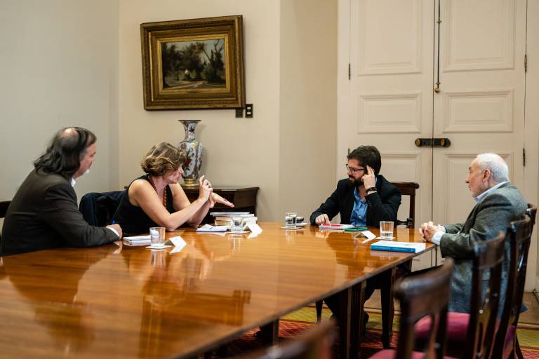 Left to right: Jose Miguel Benavente, head of CORFO, Professor Mariana Mazzucato, President Gabriel Boric, and Professor Joseph Stiglitz sitting around a wooden board table in discussions