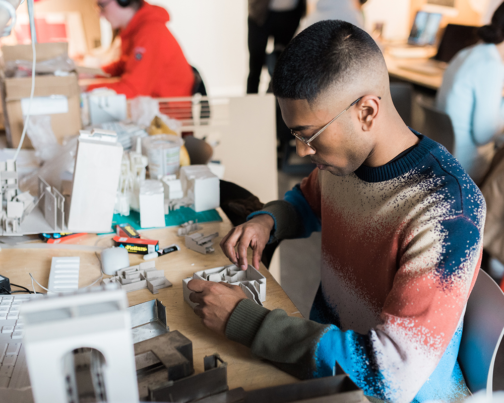 A student creating an architectural model in the studio