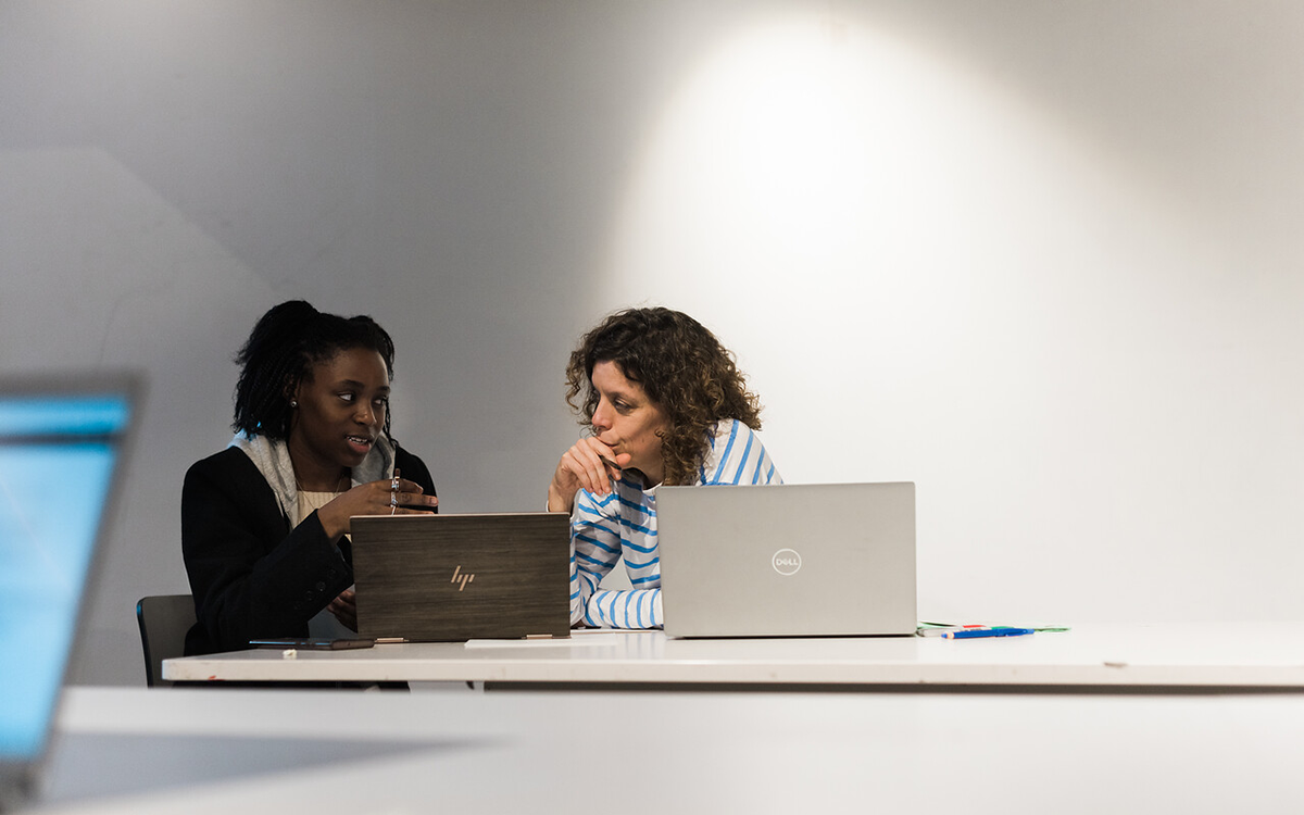 two women with laptops having involved discussion