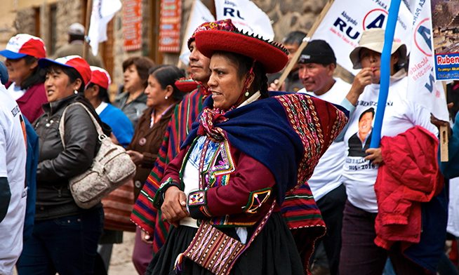 a person in traditional dress walks as part of a group demonstration
