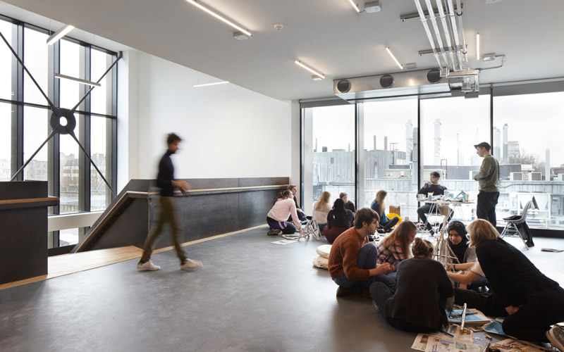 Students working in a large open plan room with views over London