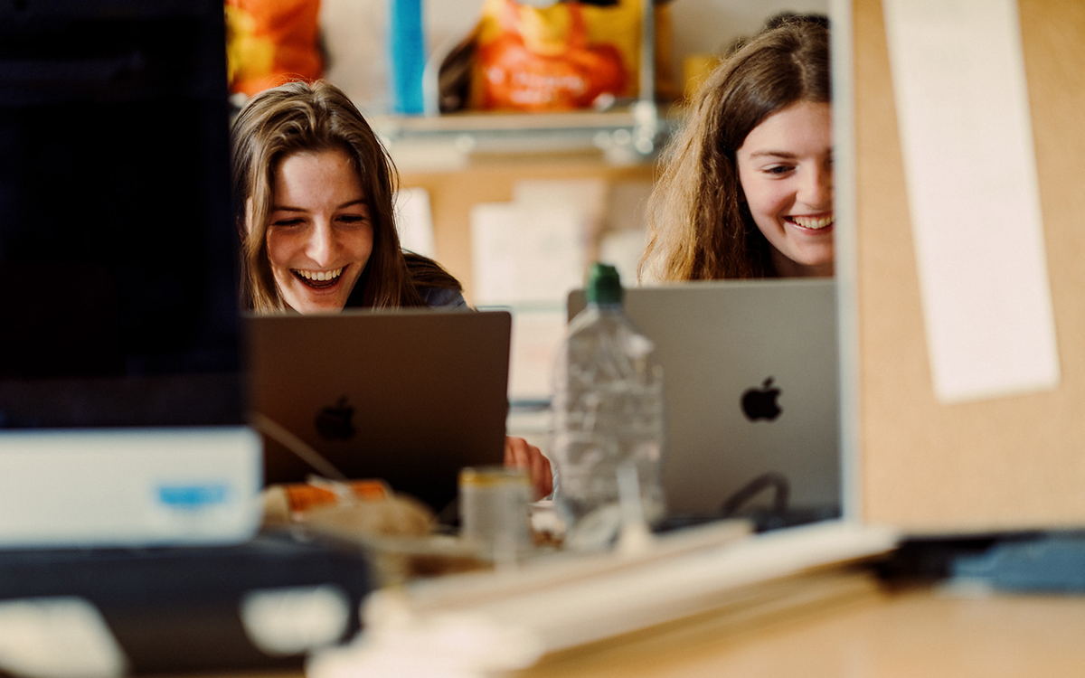 two young women at laptops laughing