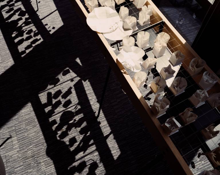 Aerial picture of students work in 22 Gordon Street with light casting a shadow of paper structures onto the carpet floor