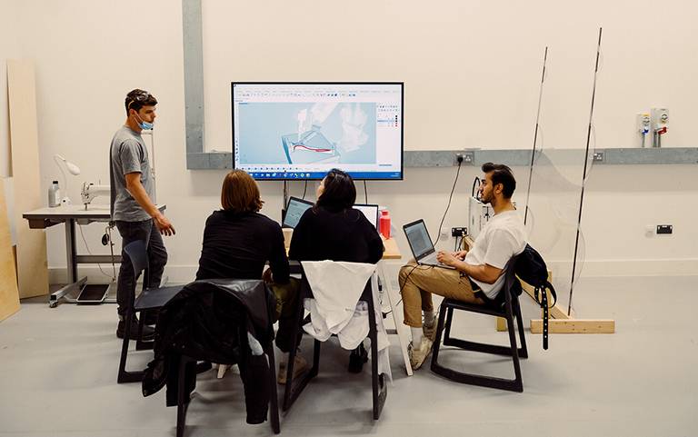 group of students talking in front of 3D image on computer