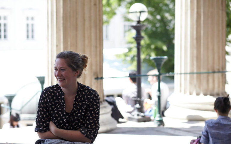 A woman sits in the UCL portico
