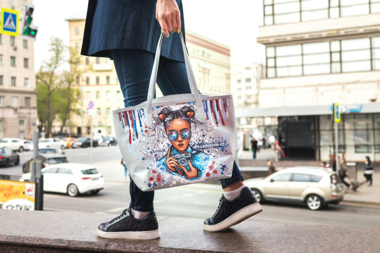person walking with tote bag, with comic book style drawing of woman with camera printed on it