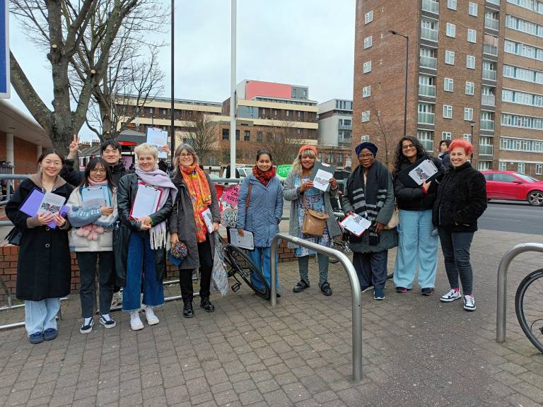 Diverse group of women holding papers standing outside residential estate with high-rise buildings