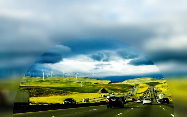 Cars in traffic with wind turbines on the horizon