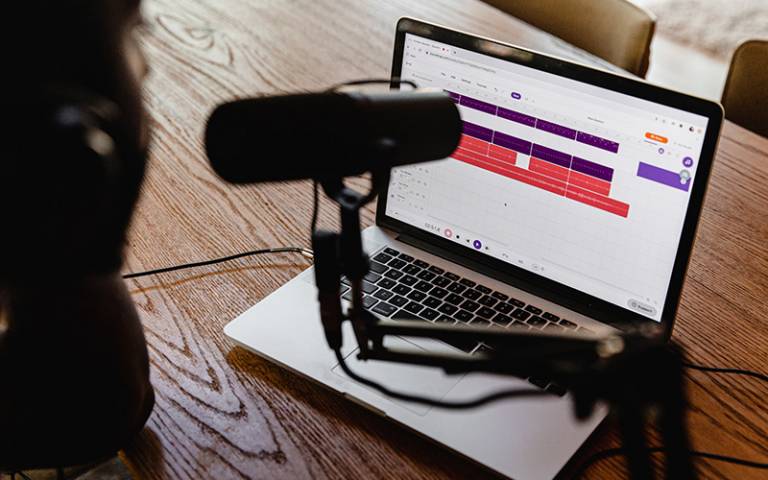 Image of laptop and podcast microphone on wooden table