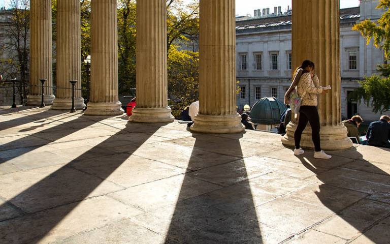 Student walks across the portico at the UCL Wilkins Building