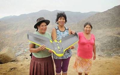 Three ladies holding a drone in a mountain landscape