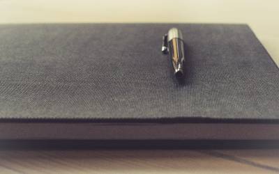 Image of a pen resting on a black notepad
