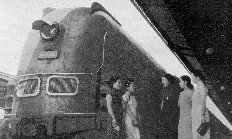 People stand in front of the Asia Express, an early prototype of the Japanese bullet train