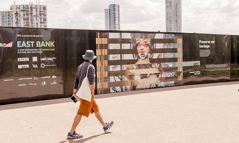 A person walks past colourful hoardings in East London