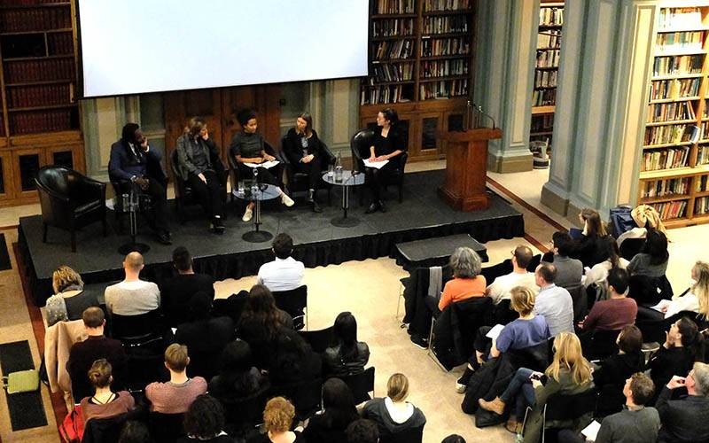 Top down view of panel discussion in large library with large seated audience