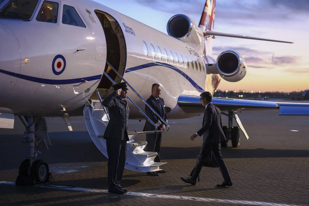 Rishi Sunak dressed in suit, approaching stairs of small plane