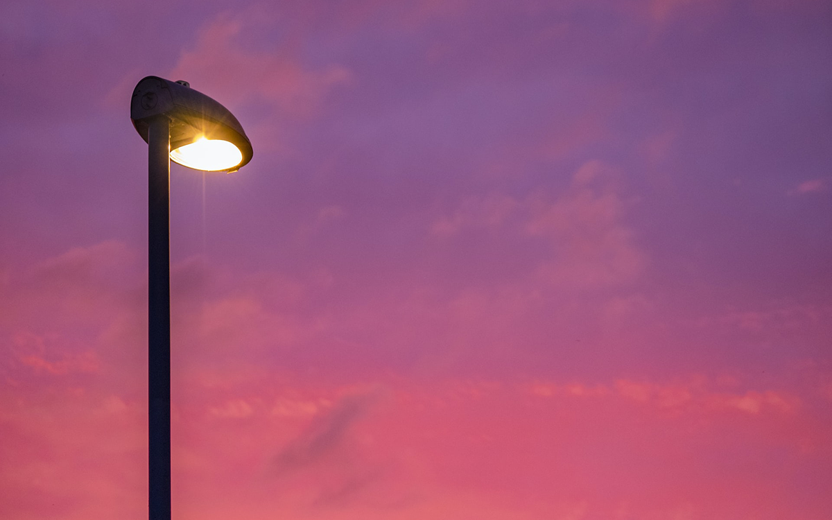 illuminated lamp post against pink dusk or dawn sky
