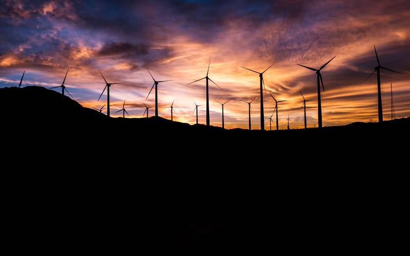 A wind farm silhouetted against a beautiful sunset