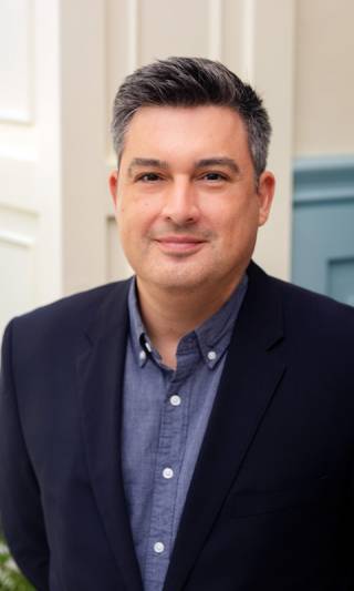 A profile image of Dr Brian Garcia who is wearing a blue shirt and navy jacket
