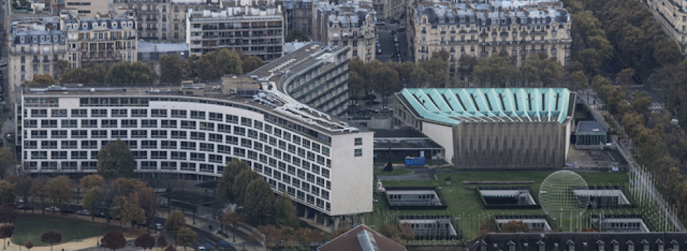 View of large building from above, 3 long structures extending from central point next to shell shaped building (viewed from above)