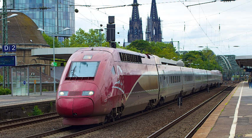 Modern passenger train with Kolm cathedral in background