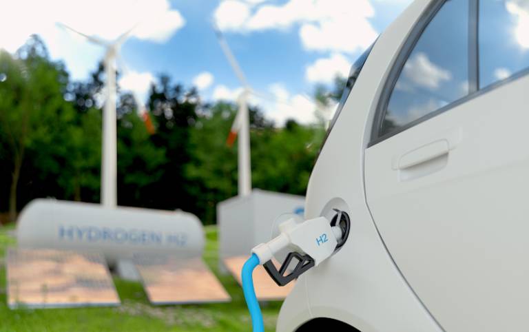 Hydrogen fuel charging of a car with wind turbines in the background