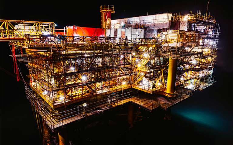 Oil platform in the sea covered in scaffolding at night