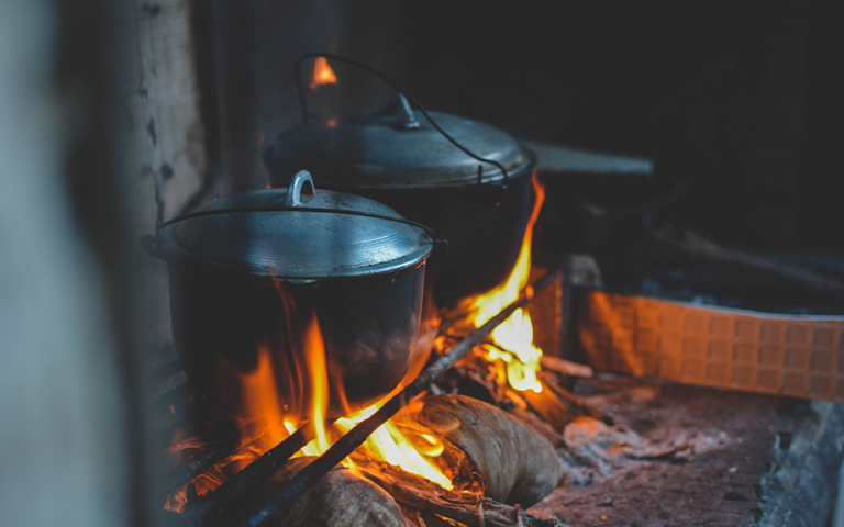 Two lidded pans on an open fire 
