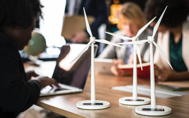 Wind turbines on a desk with people working in the background