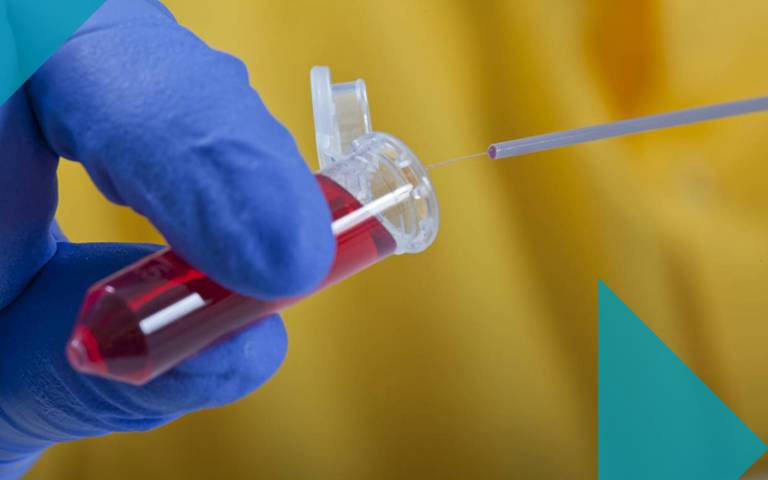 Gloved hand holding vial of red liquid