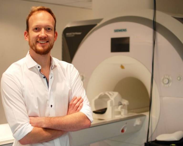 Tobias Hauser standing next to an MRI machine 