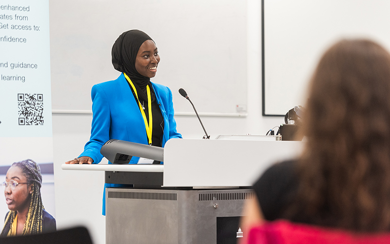 A student stood behind a lectern, smiling.