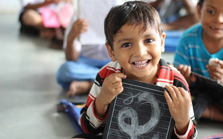 A boy smiling holding a chalkboard