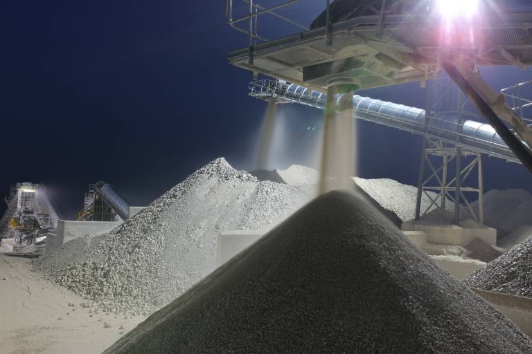 Image of concrete aggregate being processed on a large scale using machinery against the night sky