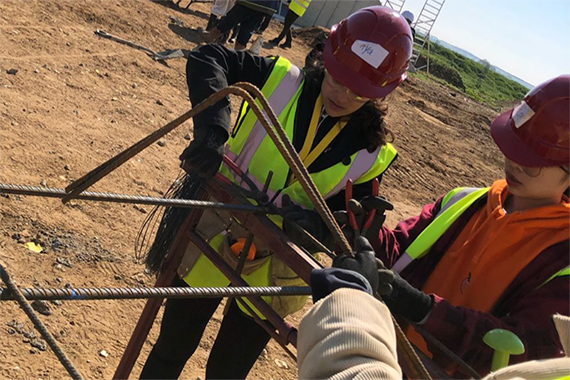 Two civil engineering students tying steel reinforcement bars 