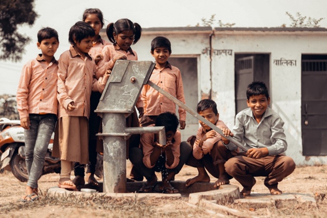 children gathering around a fountain to collect water